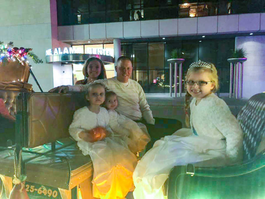 Father smiles and he sits on horse and carriage with his two daughters and two foster daughters