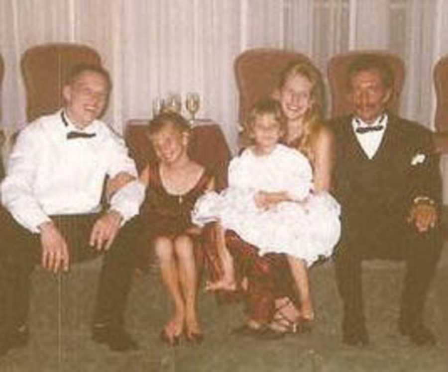 Three girls sitting between tow men in tuxedos at formal event