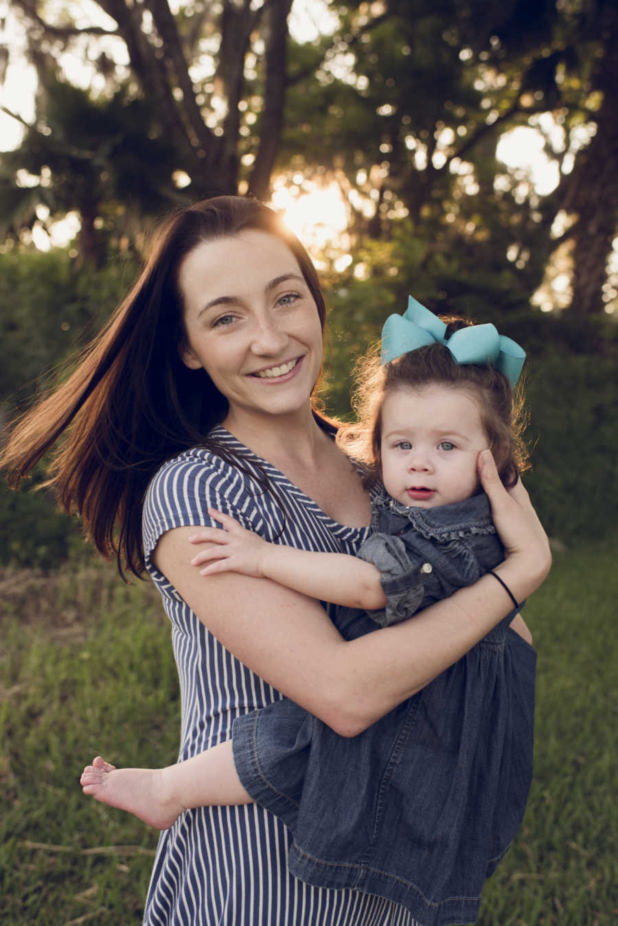 Young woman stands outside holding cousin's daughter who she took in