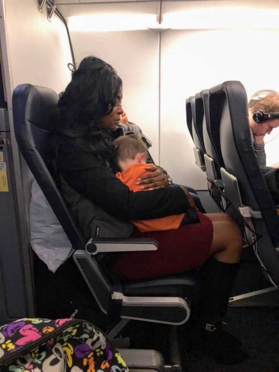 Woman sitting on airplane with little boy in her lap whose mother is overwhelmed flying with her kids