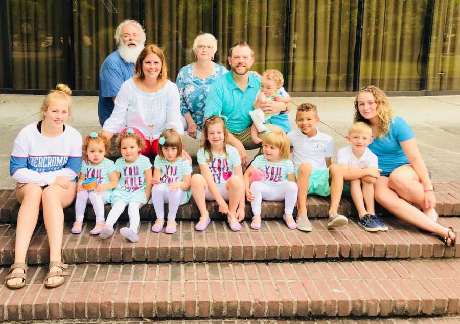 Husband and wife sit beside their biological kids and eight adopted children beside elderly couple