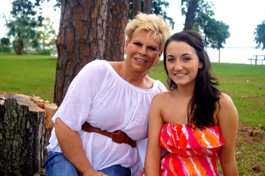 Young woman sits smiling beside her mother outside