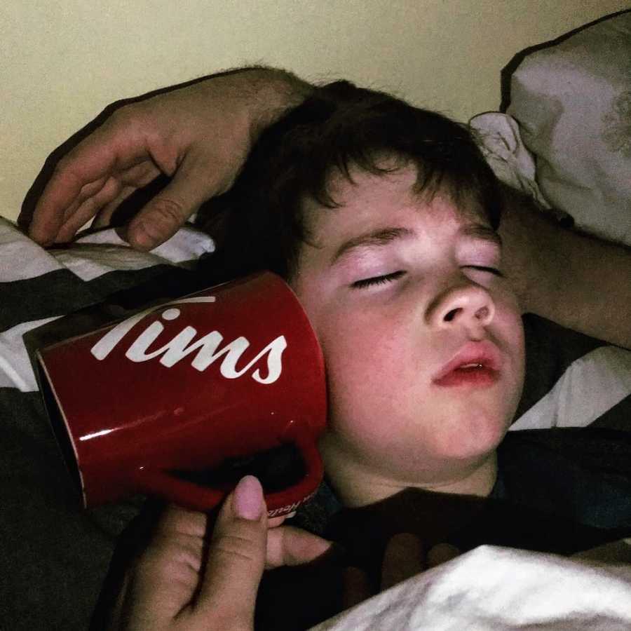 Mother holding up mug to little boys ear who has ear infection