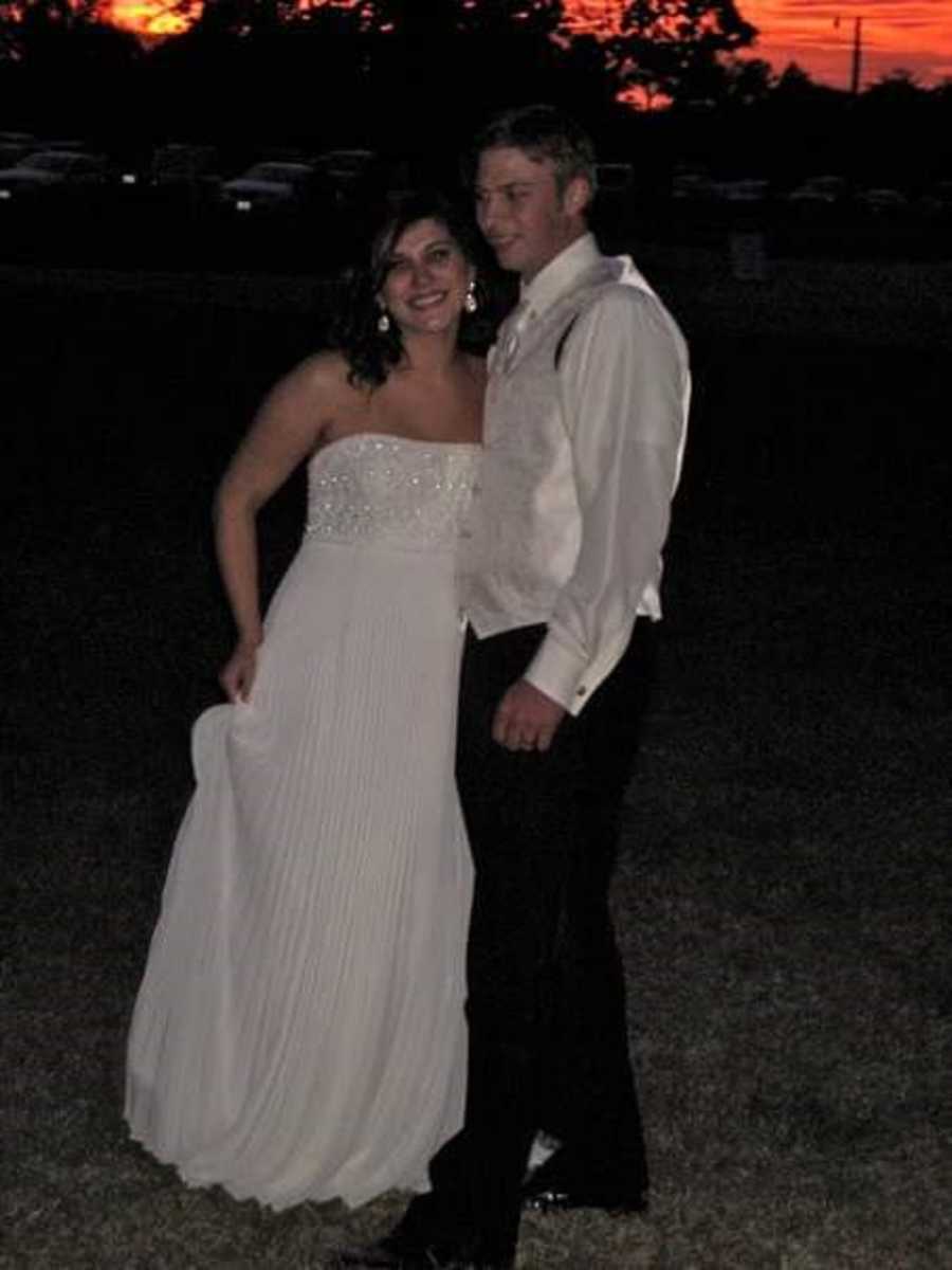 Husband and wife stand outside at night smiling in formal attire