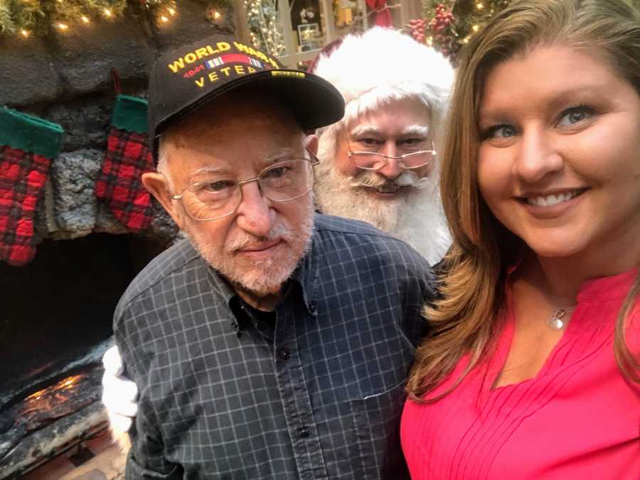 Woman smiles in selfie with WWII veteran and mall Santa