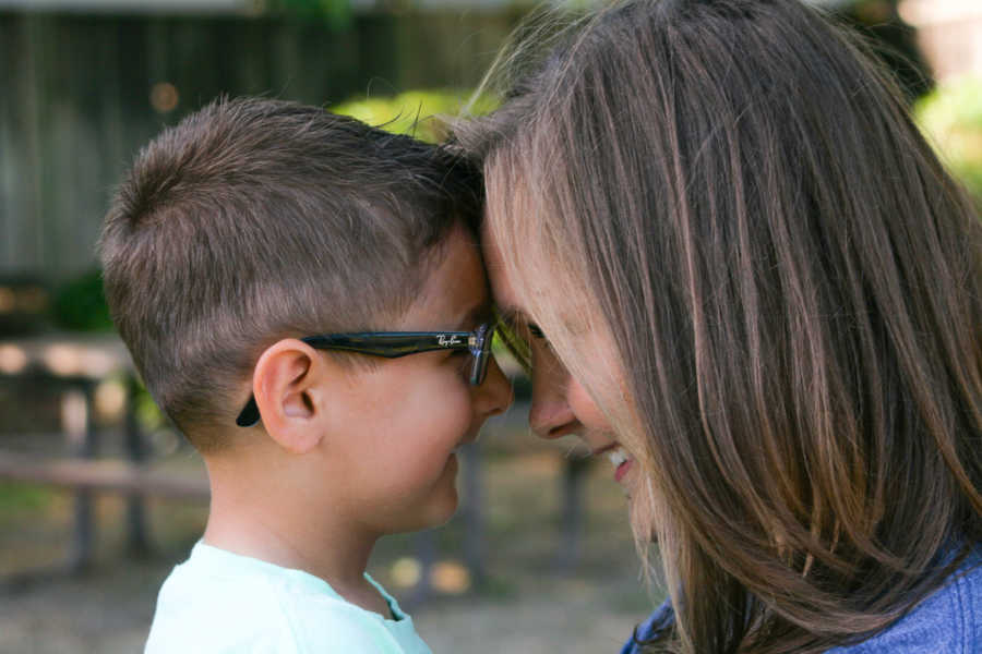 Mother and son's head touch as they smile at each other