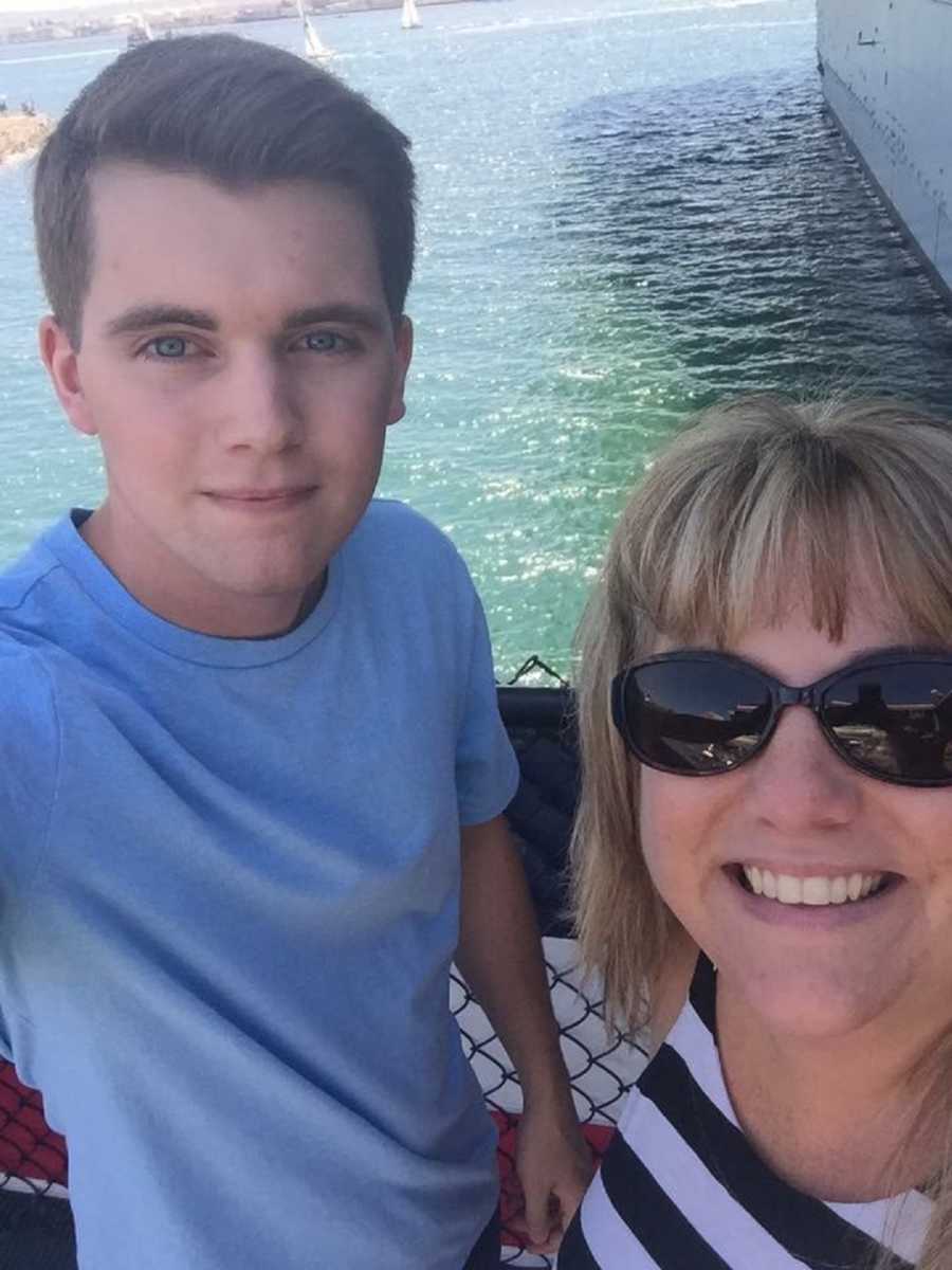 Mother smiles in selfie with son and body of water is in background