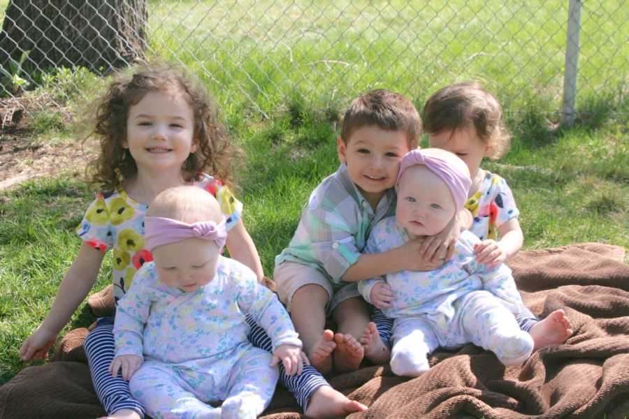 Little boy whose mom is scared will lose his sweetness sits on blanket outside with four siblings