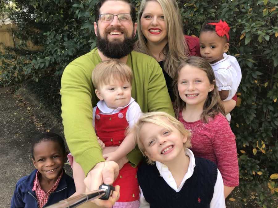 Wife who asks for husband's help during holiday season smiles outside with him and their five children