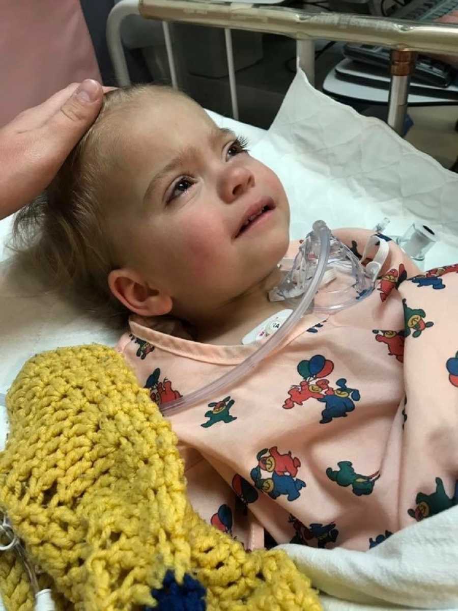 Little girl with multiple illnesses lays in hospital bed on her back
