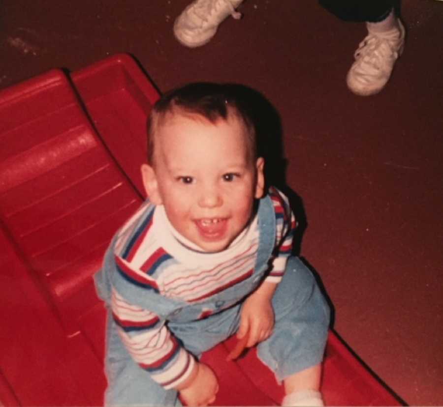 Little boy looks up smiling as he sits in red sled and passed away at young age