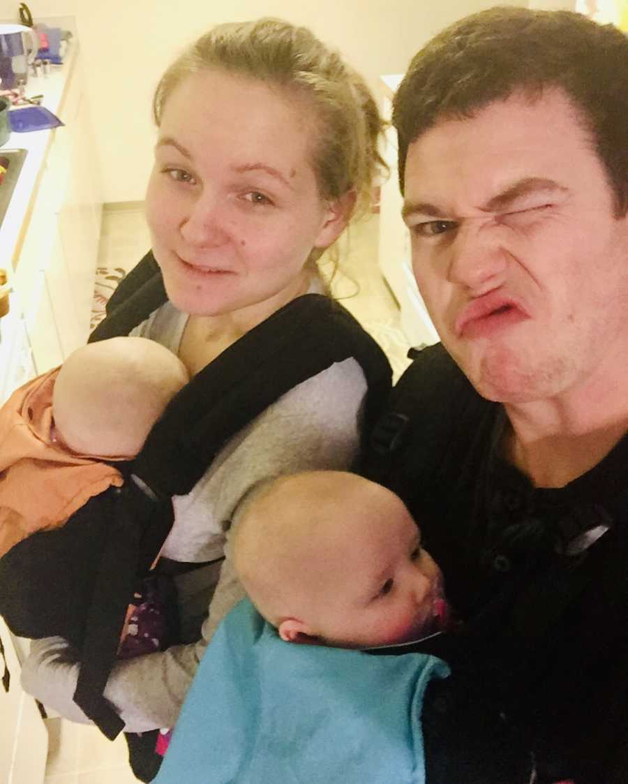Husband and wife take selfie with a baby swaddled to each of their chests
