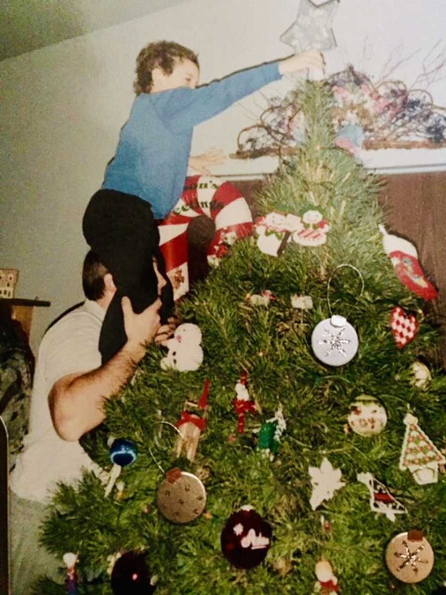 Father holds up son who has since passed away to put star on Christmas tree 