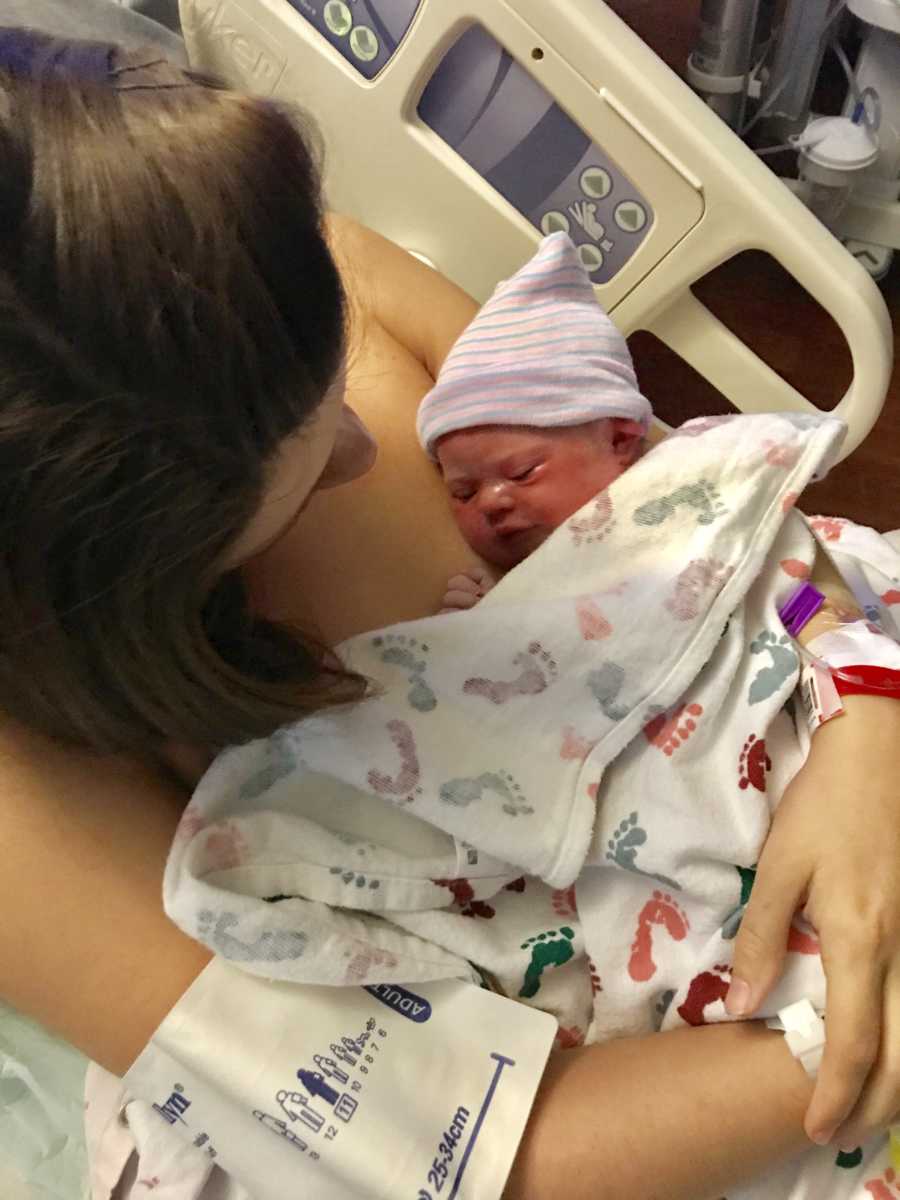 Mother laying in hospital bed holding newborn to her bare chest