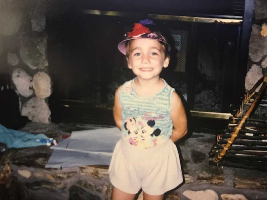 Little girl who was put up for adoption stands smiling in home in front of fire place