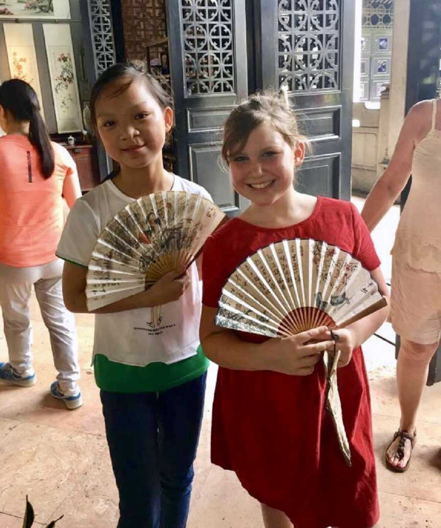 Sisters stands holding Chinese fans at Chinese adoption center