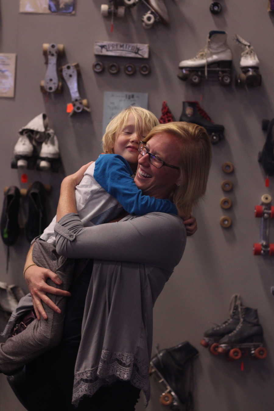 Birth mother holds and hugs son she gave up for adoption in front of wall with roller blades 