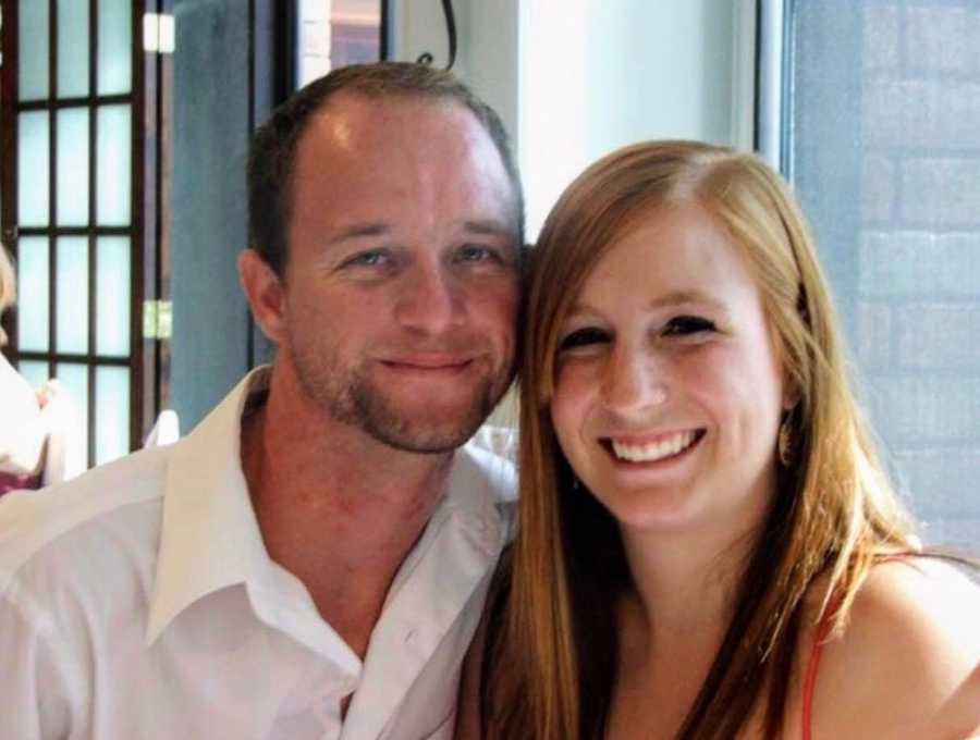 Husband who makes a point to clean his wedding ring smiles beside wife in restaurant