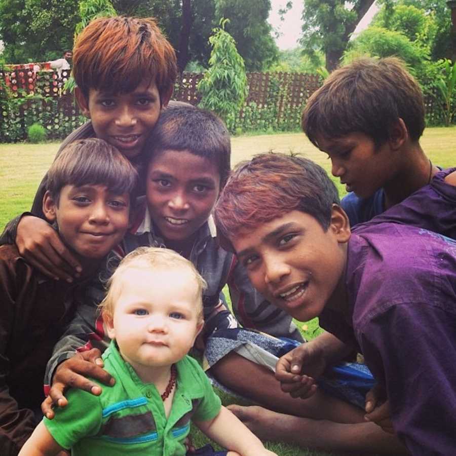 Baby boy sits on ground with little boys at Indian child care center