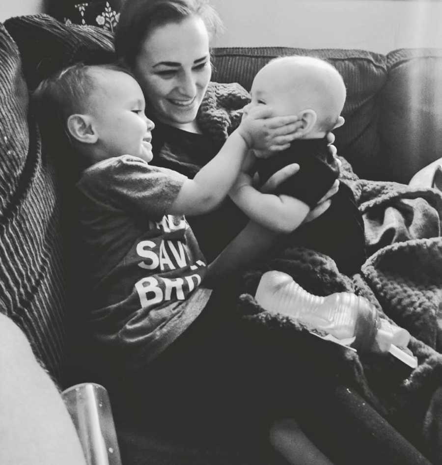 Mother sits on couch with toddler daughter and baby son who has since passed away