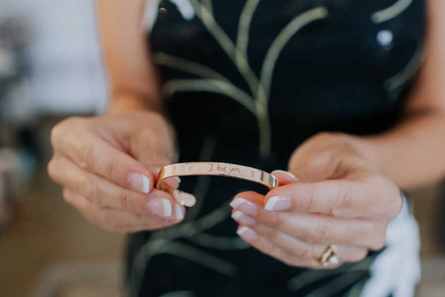 Close up of mother of groom gift which is gold bracelet engraved with son's handwriting 