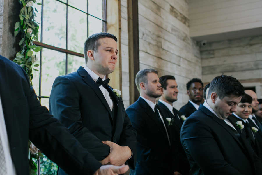 Groom tears up beside his groomsmen as he stands at altar