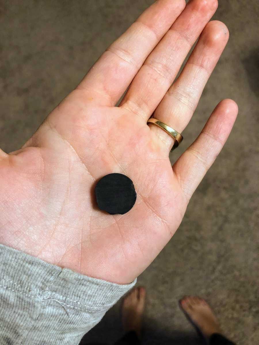 Small circular magnet in mother's hand that young daughter said she ate