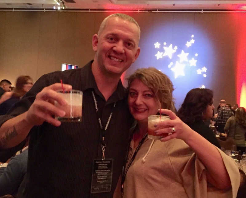 Husband and wife hold up cocktail at event