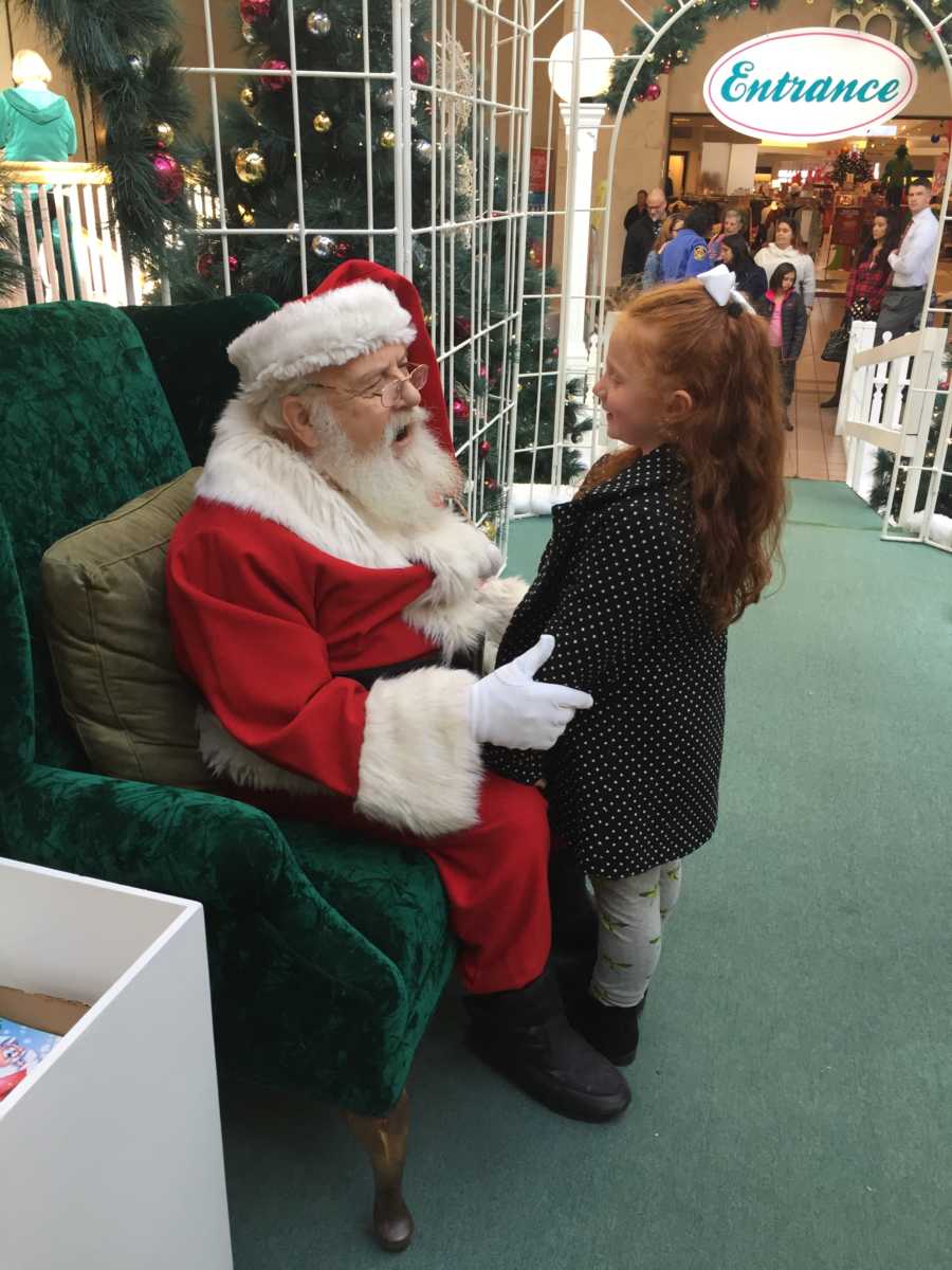 Little girl standing in front of mall Santa asking him to put a baby in mom's belly