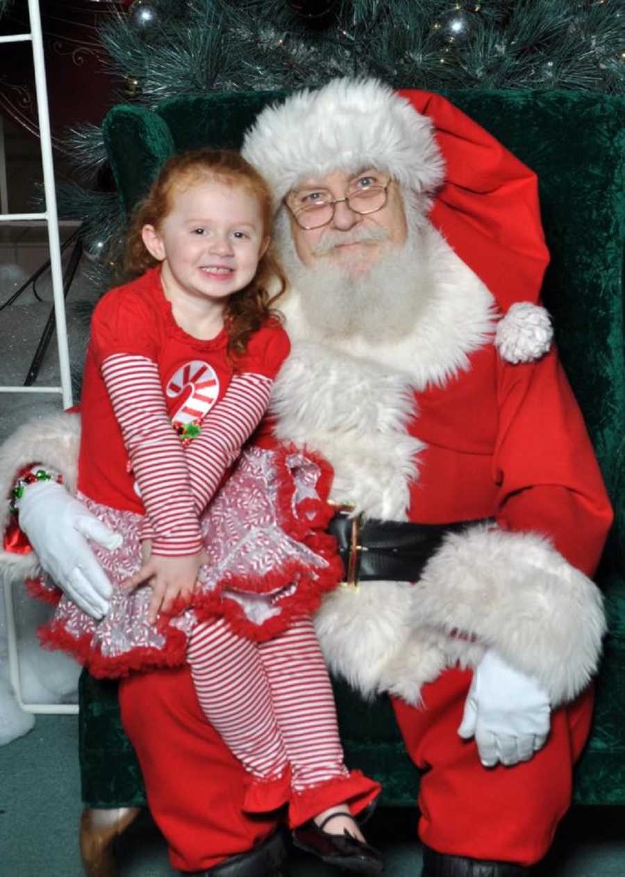 Little girl sits on mall Santa's lap