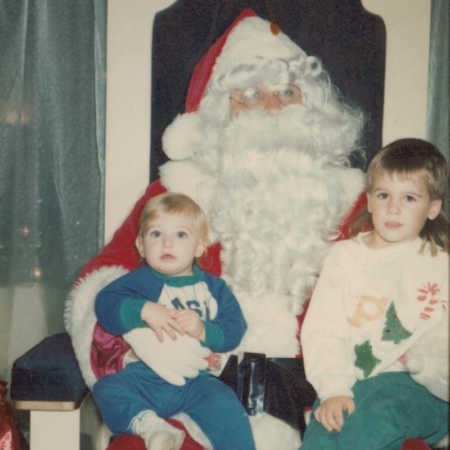 Mall Santa sits with two young kids in his lap