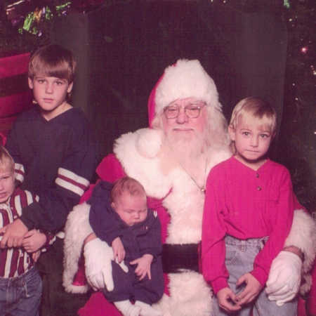 Mall Santa sits with two children in his lap and two standing beside him