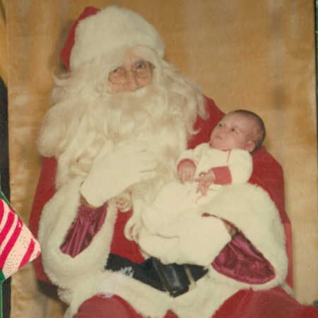Mall Santa sits holding baby in his arms