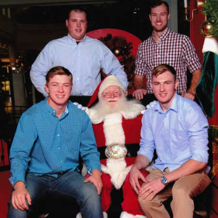 Mall Santa sits beside two young men and two men standing behind them