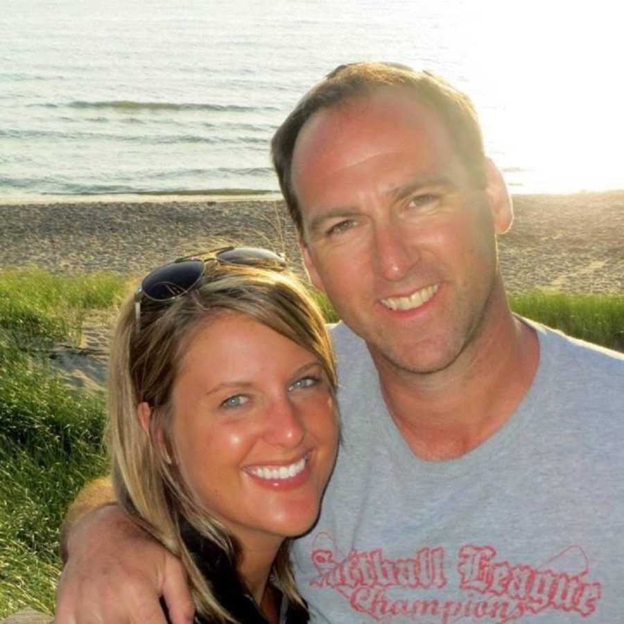 Husband and wife who are infertile stands smiling with Lake Michigan in background