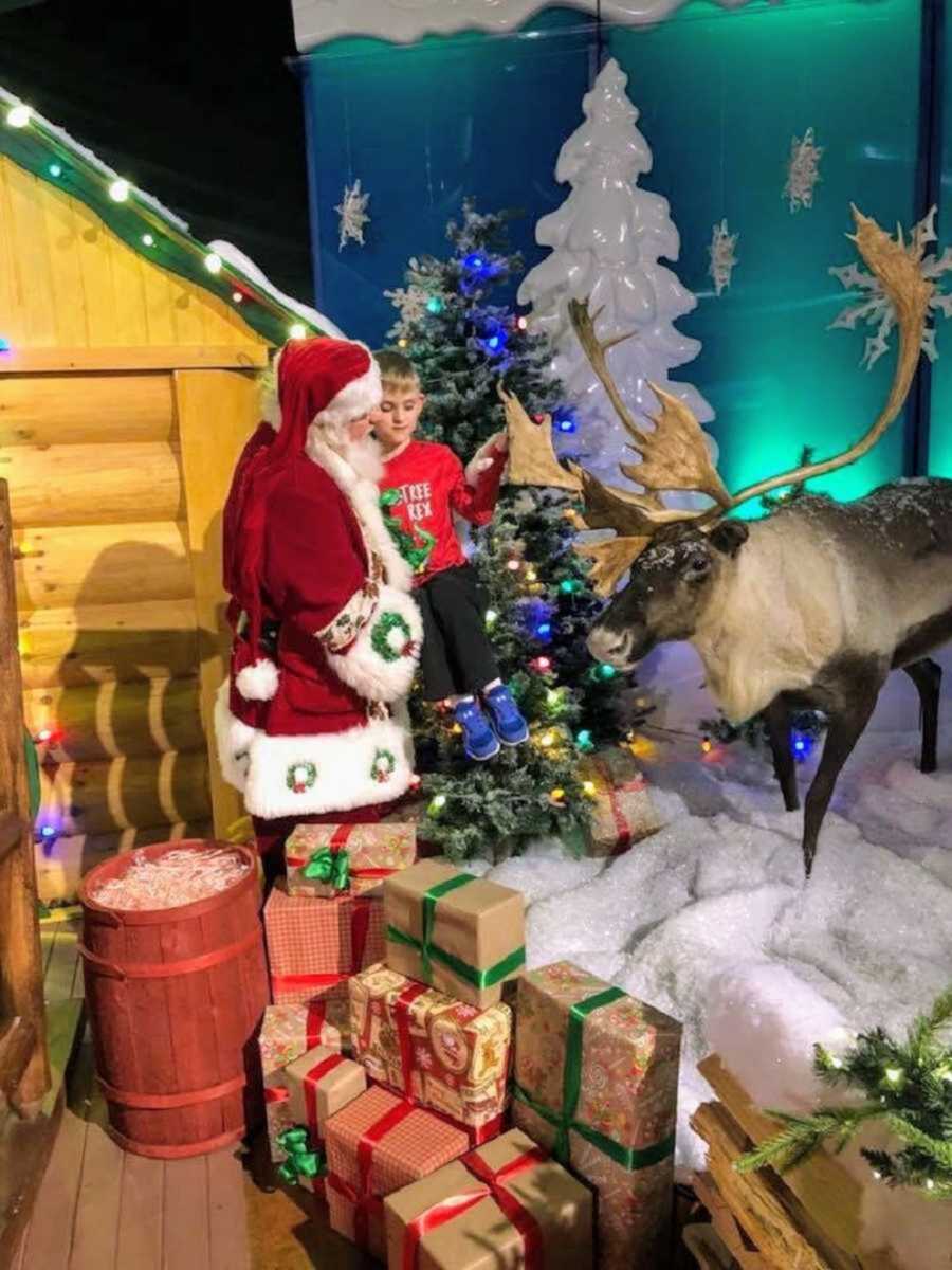 Santa holds blind boy and helps him feel reindeer