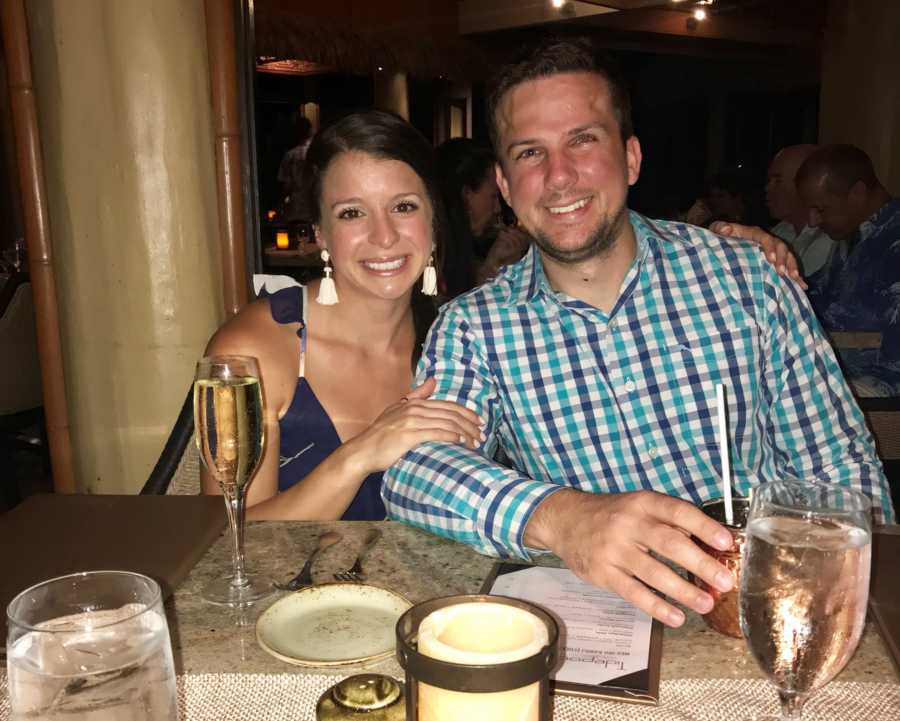 Husband and wife sit at restaurant table smiling