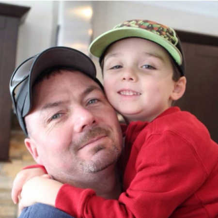 Father who has since passed from colon cancer smiles as he holds toddler son