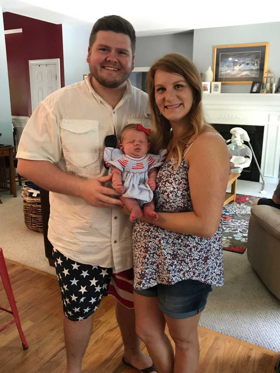 Husband and wife stand in home holding baby daughter who has mild form of dwarfism