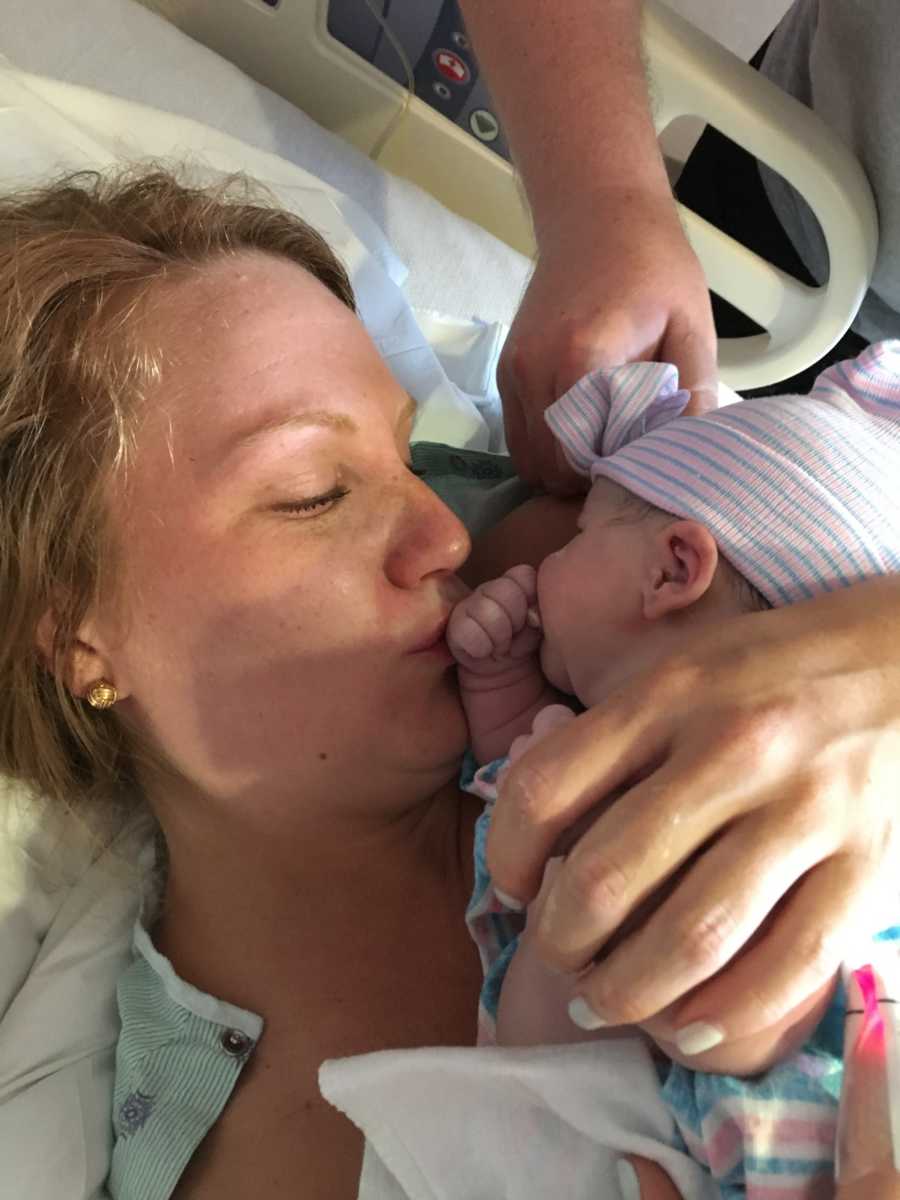 Mother lays in hospital bed kissing newborn