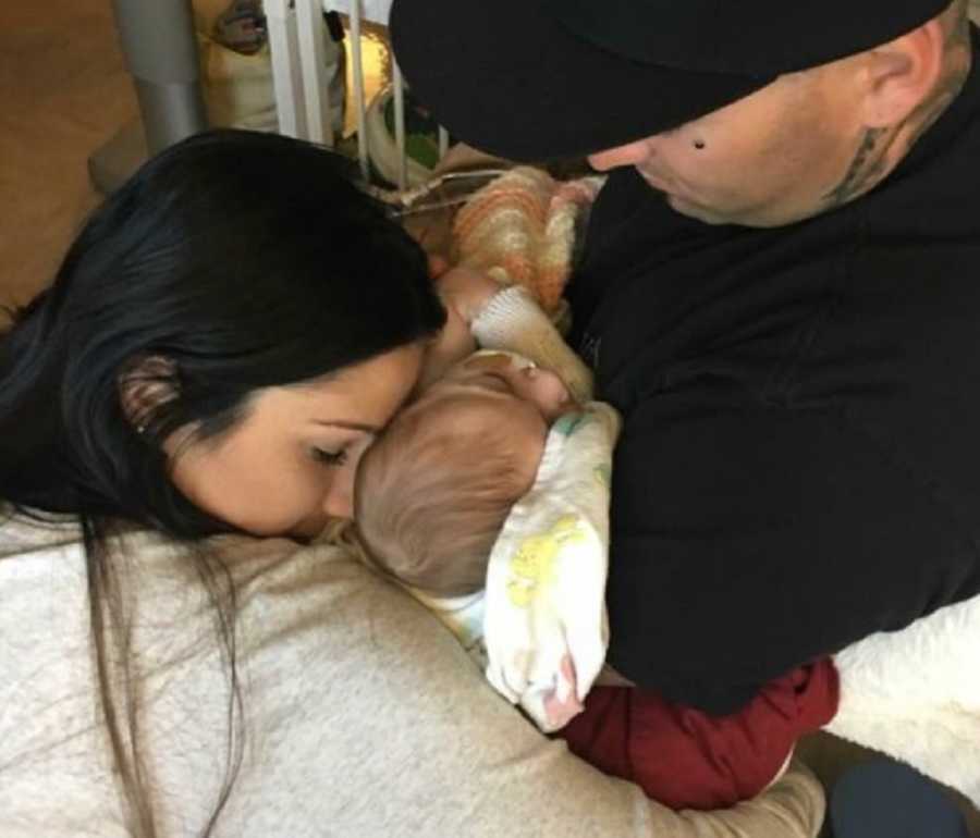 Father holds newborn with Lissencephaly as wife leans over hugging them