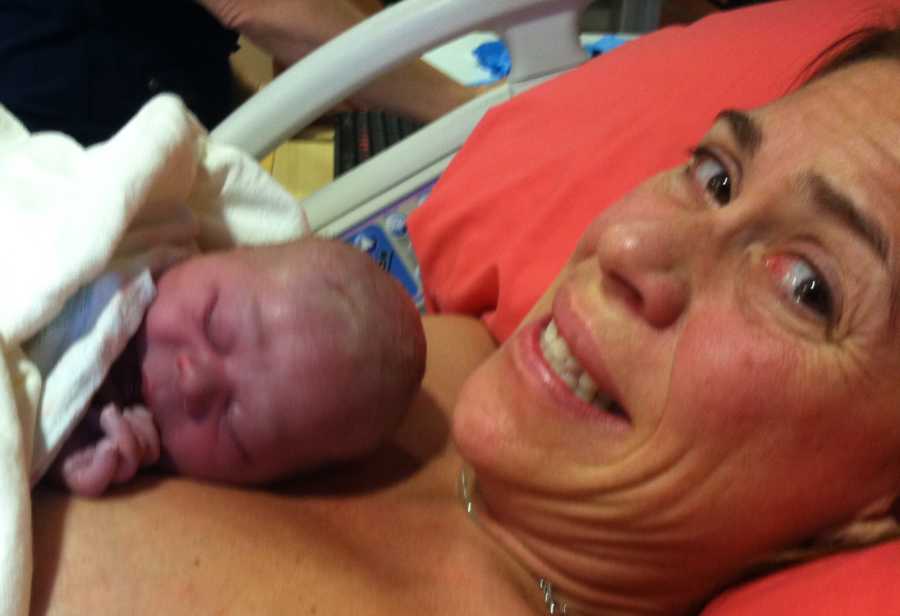 Mother looks to the side smiling as newborn she thinks has down syndrome lays on her chest