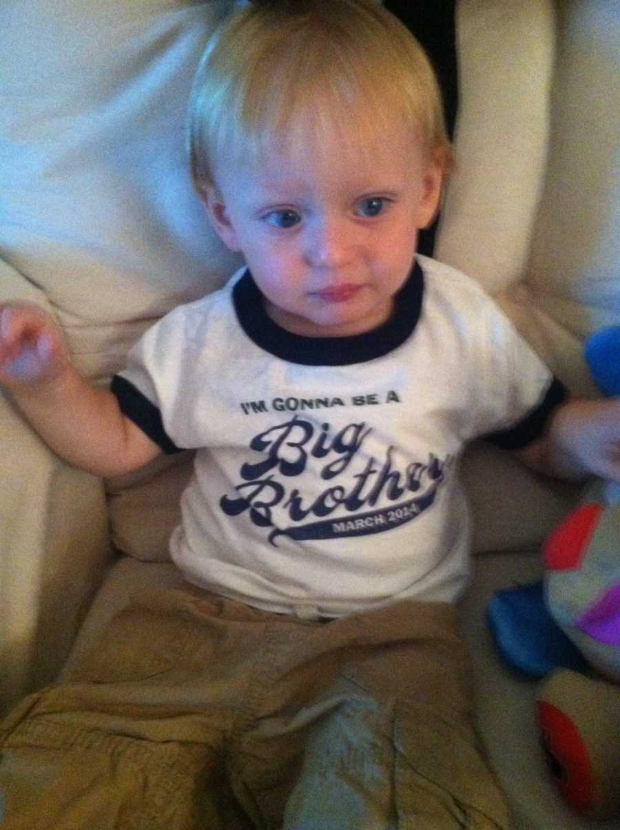 Little boy sitting on couch wearing t-shirt that says, "I'm gonna be a big brother"