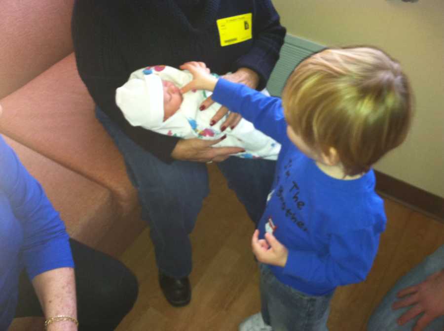 Young boy stands touching newborn sister whose mother thinks has down syndrome