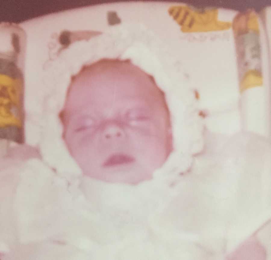 Close up of newborn sleeping in white dress and white hat