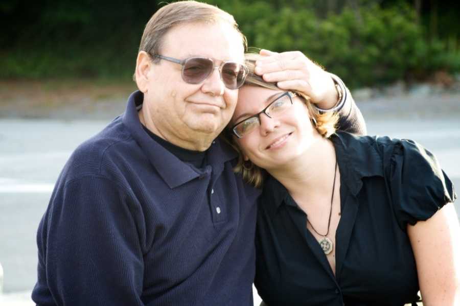 Father with stage 4 cancer sits smiles as he sits beside daughter with hand on her head