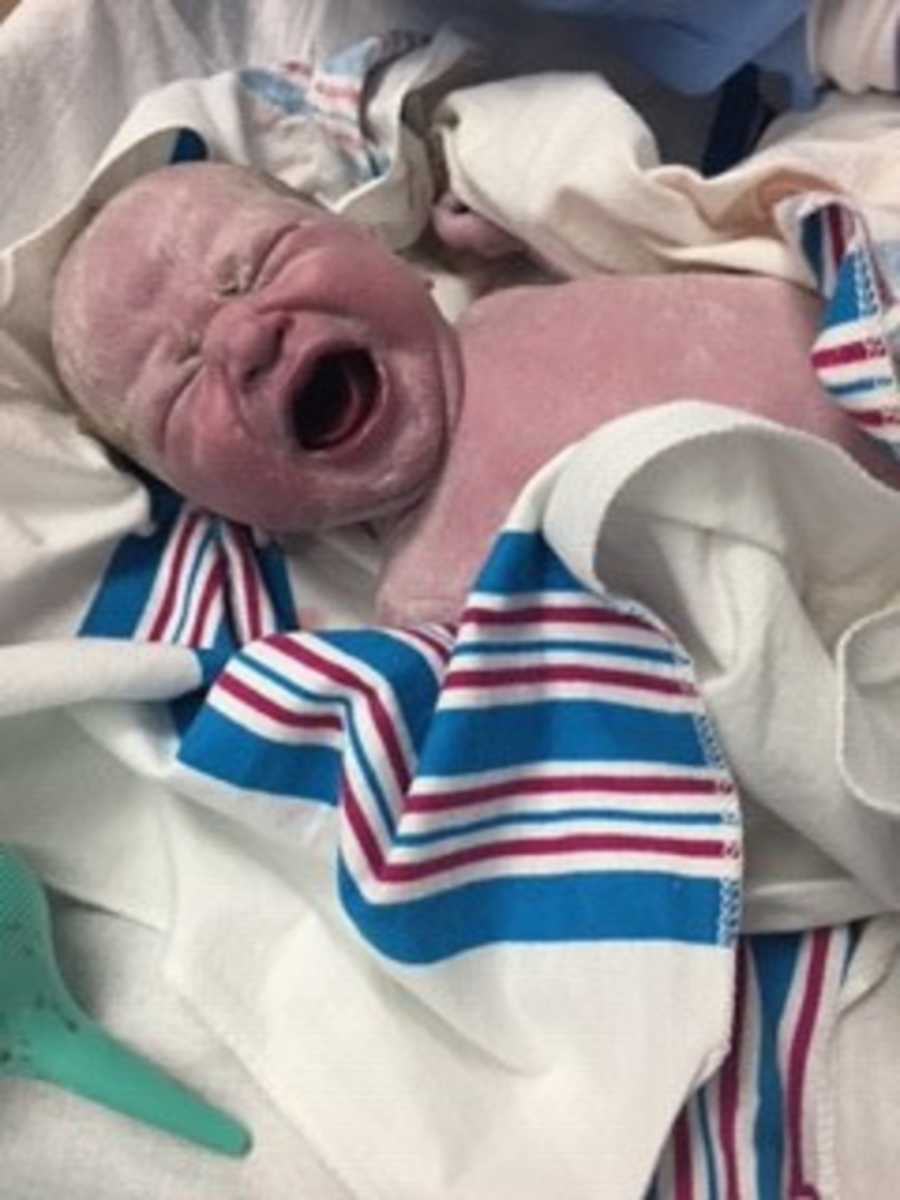 Adopted newborn baby crying wrapped in blanket