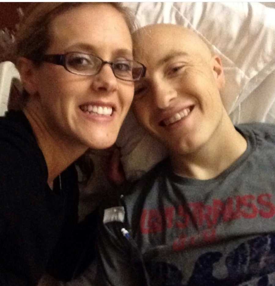 Wife smiles beside husband who lays in bed with leukemia 