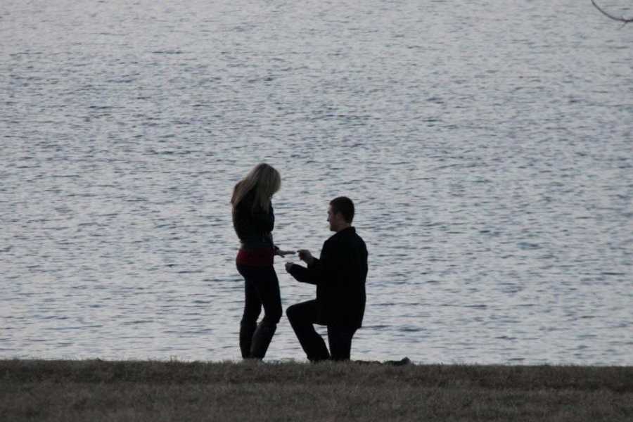 Man proposing to woman with body of water in background