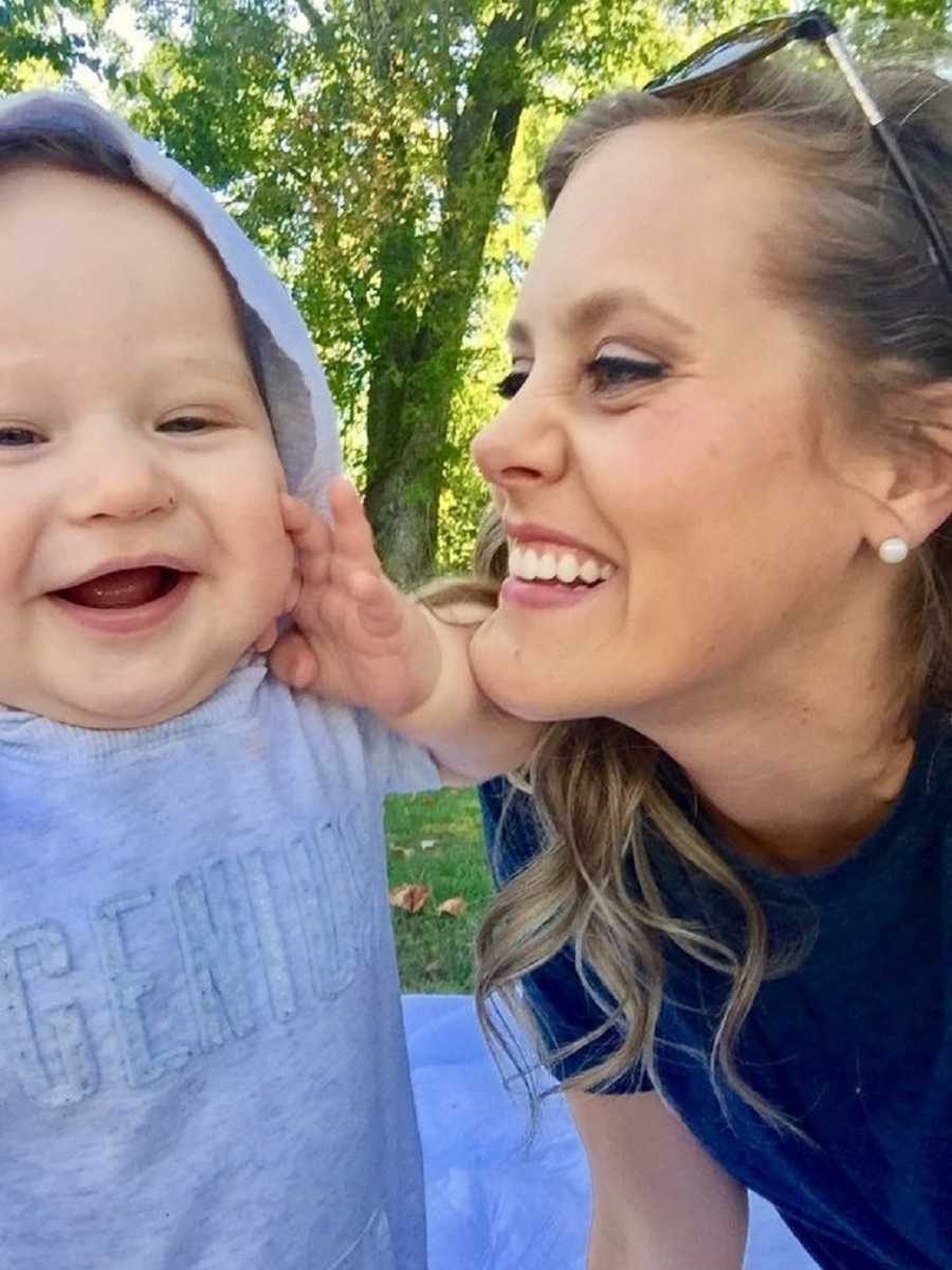 Mother smiles in selfie as she looks at adopted toddler son